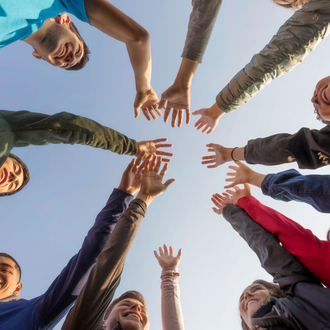 people putting all hands in a circle seen from below perspective