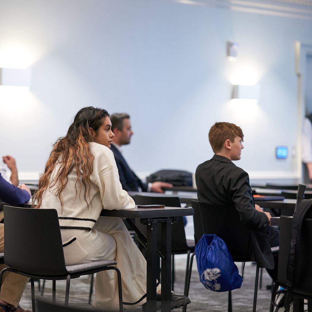 several participants and attendees sitting at tables looking at speaker 