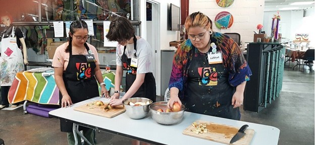 Sofia, and two other program participants cutting apples in the Van Go arts studio.
