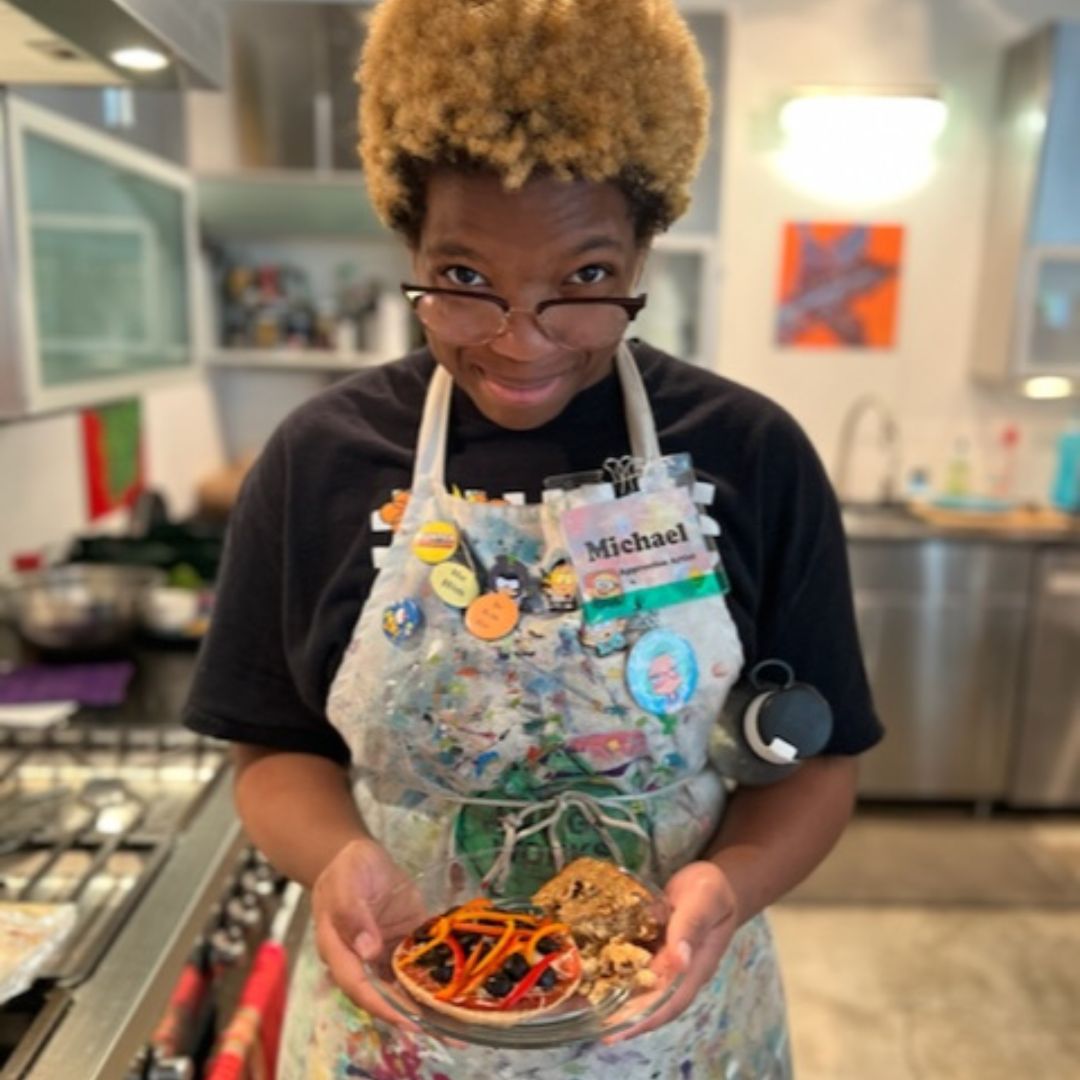 a participant of this article's cooking class proudly holding up a finished dish they created. 