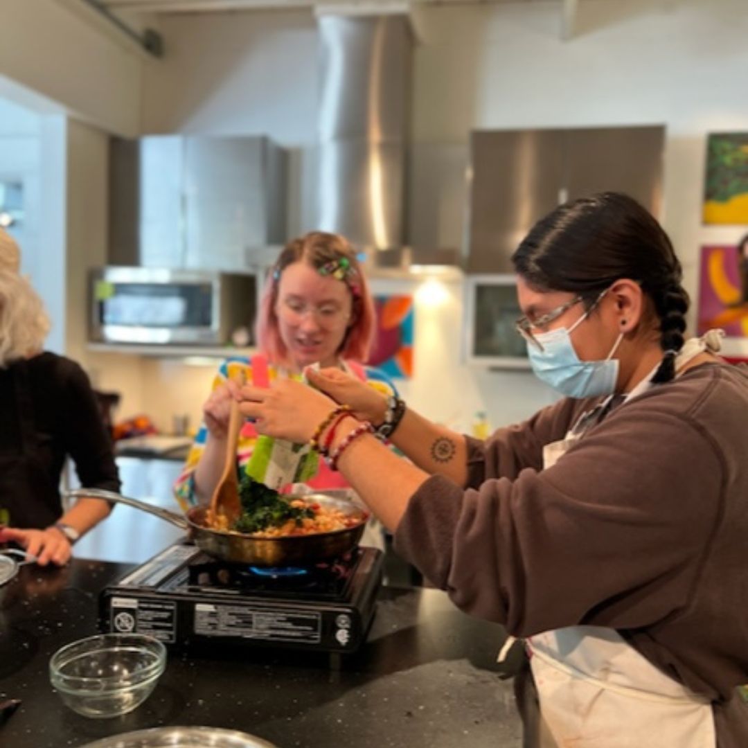 A team of two individuals cooking on a portable stove tops during the class described in this article.