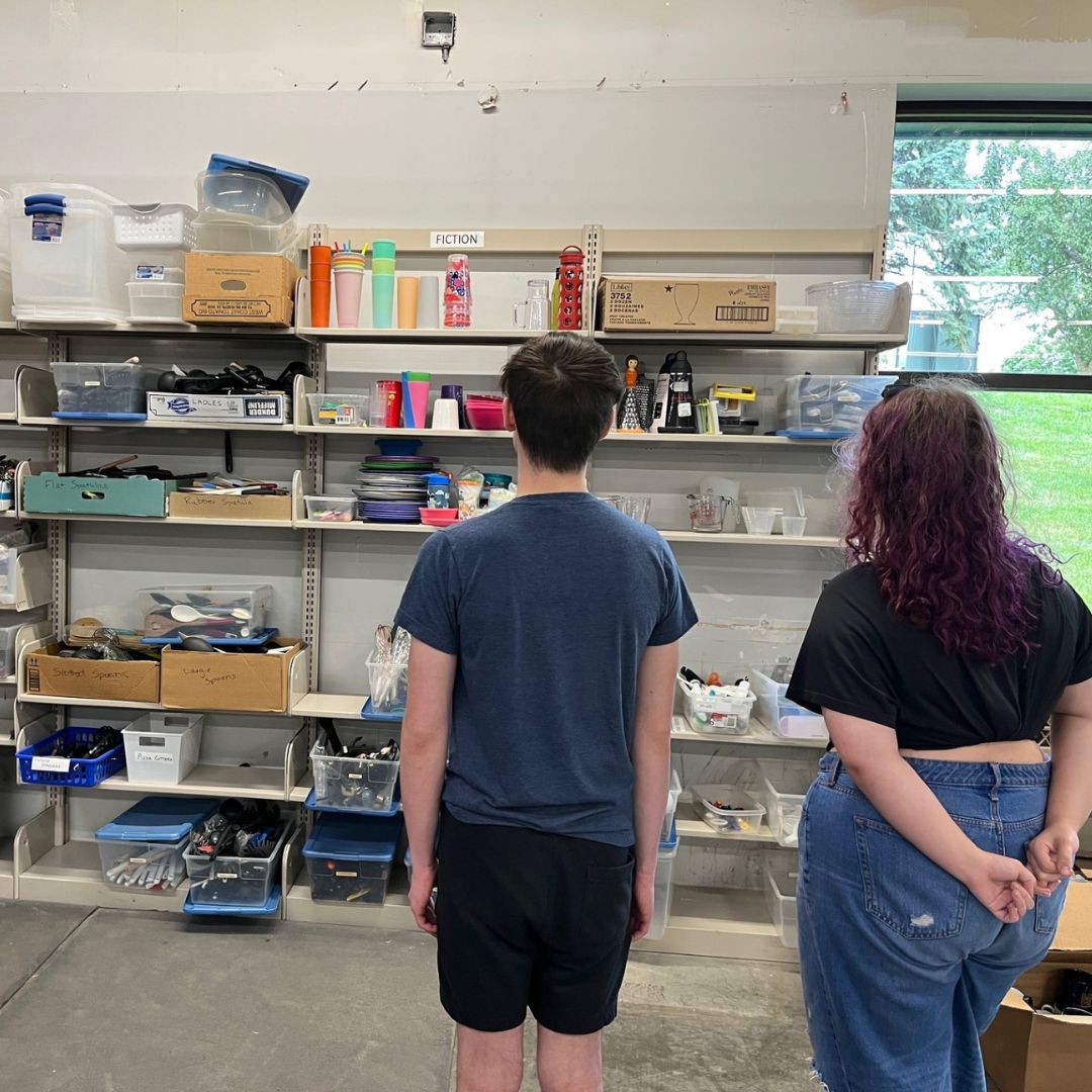 two youth looking at supplies lining a wall