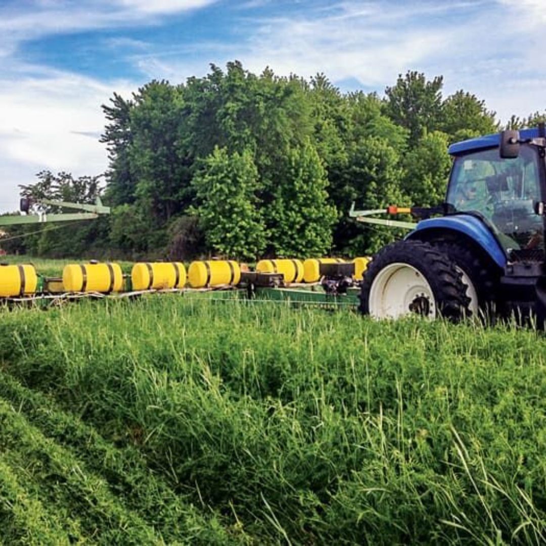machine going over a field of grass during the day
